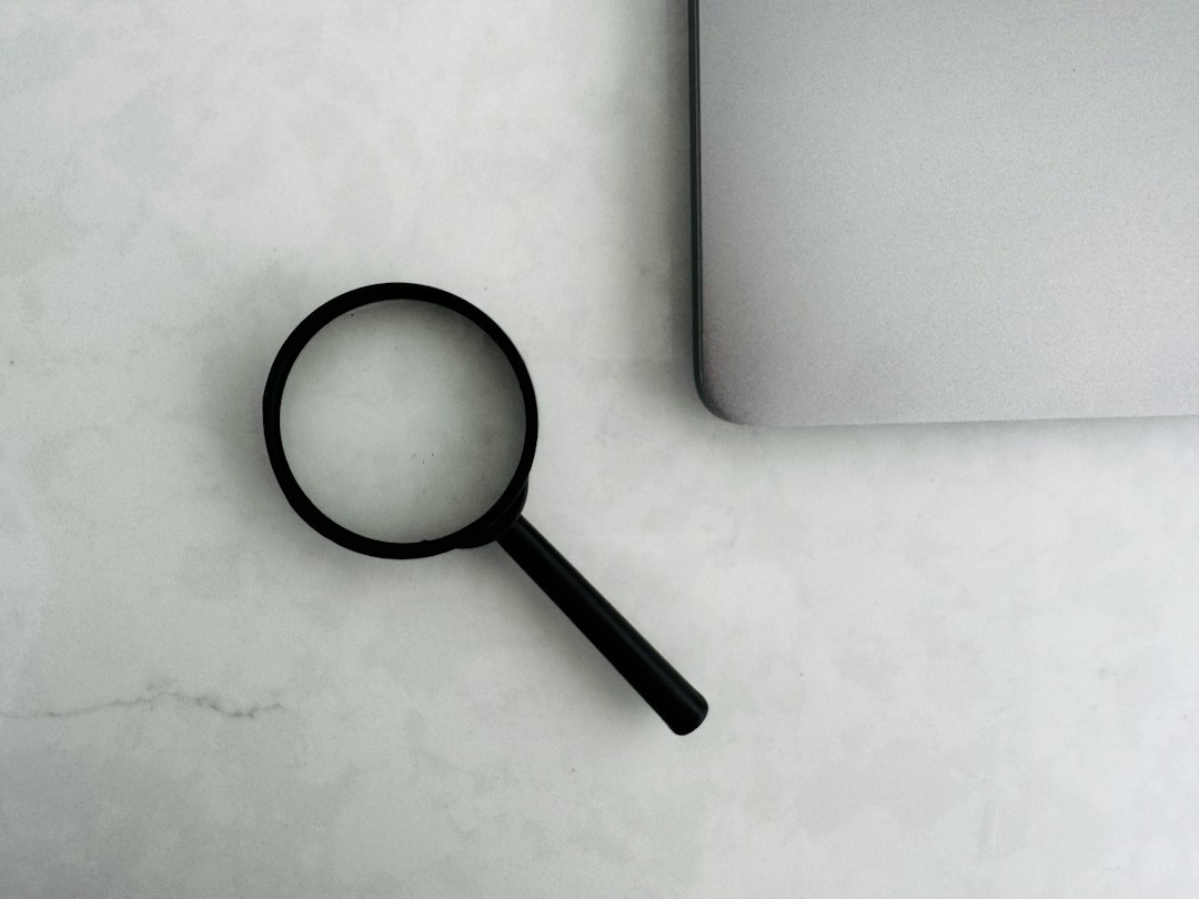 A magnifying glass placed next to a laptop on a white surface